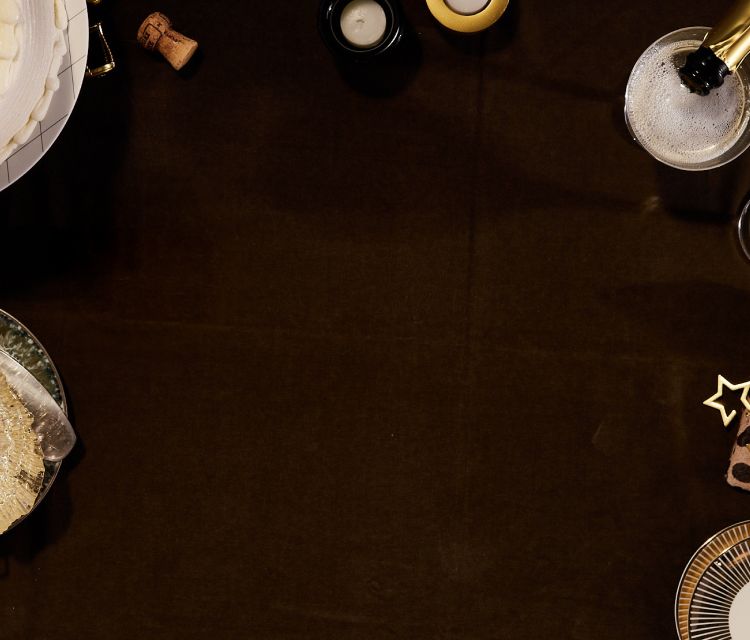 A brown cloth background framed with bubbly drinks, corks, and candles. 