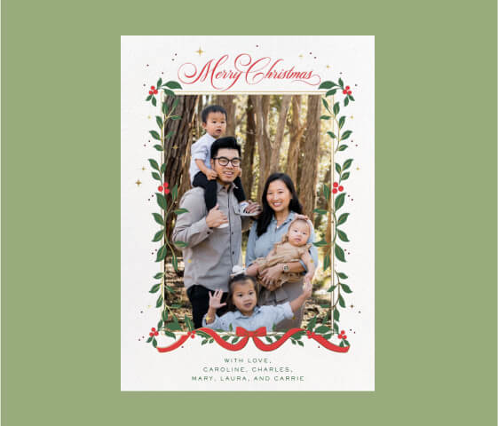 A Christmas card with a family photo, decorated with a garland of holly, and a text banner at the top reading ‘Merry Christmas.’