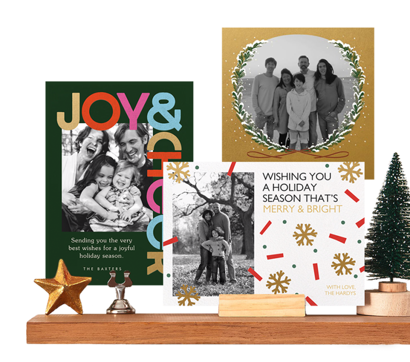 A mantel displaying three holiday greeting cards, including messages of "Joy & Cheer" and "Wishing You a Holiday Season That's Merry & Bright."