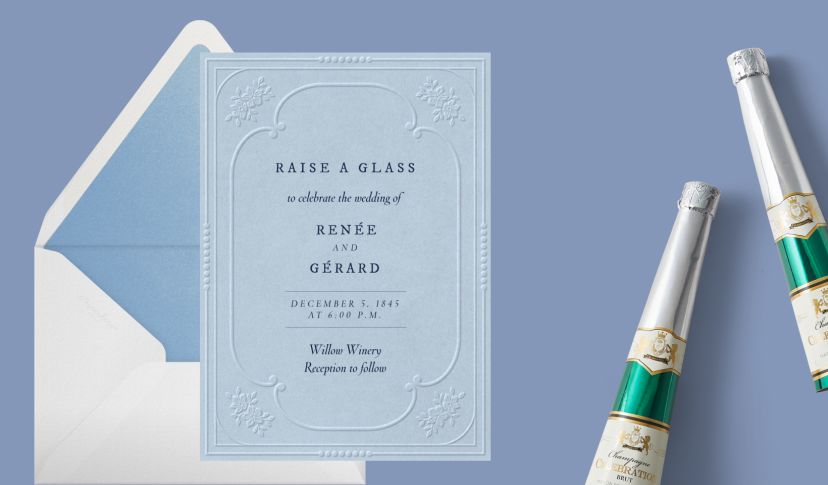 Light blue embossed wedding invitation card with classic serif typography, shown with a matching envelope and champagne bottles on a soft blue background.