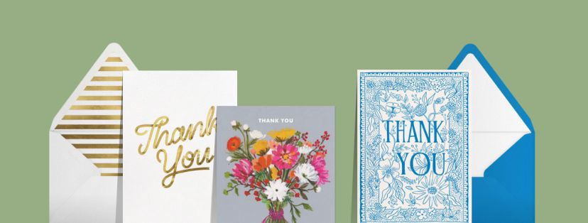 A green backdrop set with three thank you cards: a white card with gold cursive lettering, a grey card with a colorful bouquet of flowers, and a white card with blue text and elaborate blue floral illustrations. 