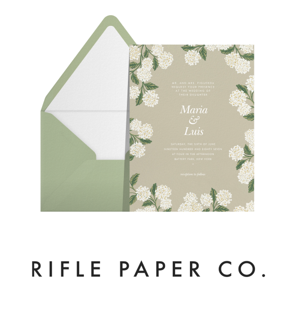 Text that reads 'Rifle Paper Co.' paired with a wedding invitation with a beige background and white hydrangea illustrated border, green envelope, and white envelope liner. 