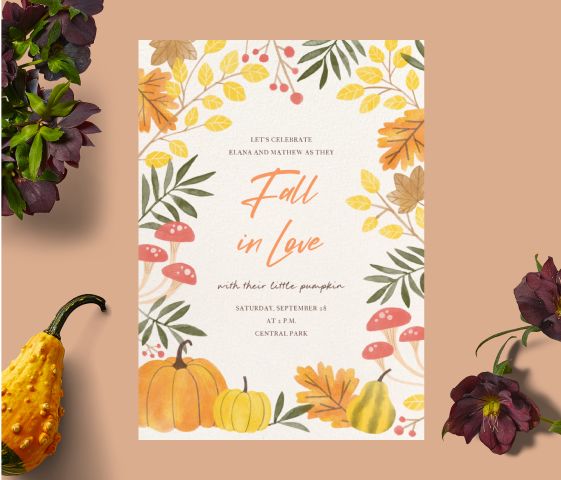 A white invitation with orange and yellow leaves, pumpkins, and mushrooms on a tan backdrop with dark purple flowers and a gourd. 