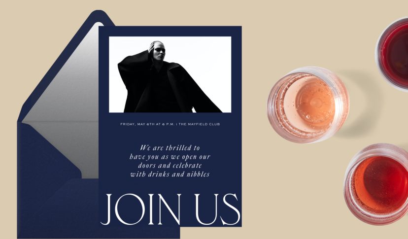 An invitation to a New Year’s Eve party with sparkly accents and drawn hands holding a disco ball and martini glass, set on a gold envelope with a black starry liner, on a tan background with two bottles of champagne. 