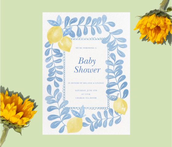 A white invitation with blue leaves and yellow lemons on a green backdrop with sunflowers. 